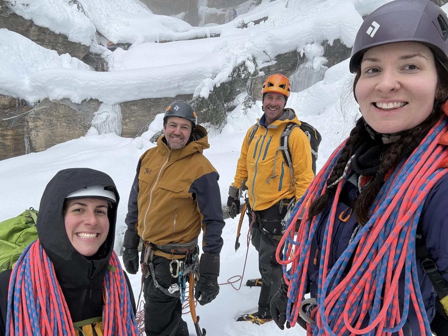Four helmeted climbers together beside the ice