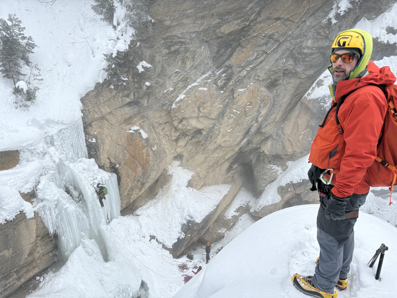 Camp host Ryan Hamilton in a red jacket, watching climbers make the first ascent of Ladies’ First Falls