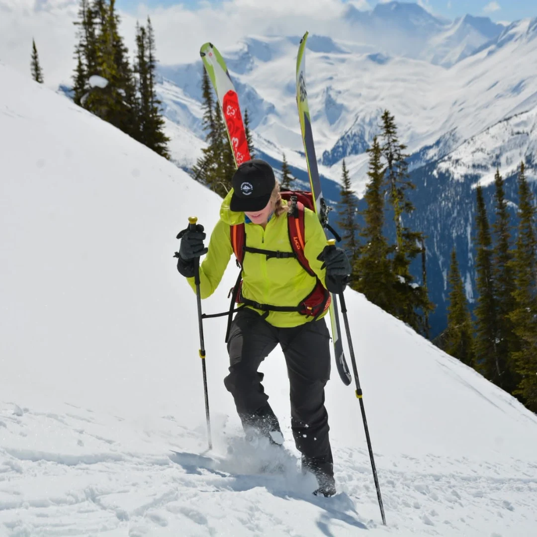 Skier climbing through deep snow with skis carried on a backpack
